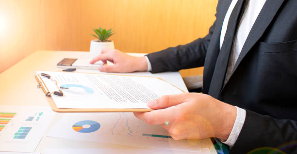 A person sitting at a table with papers and a laptop.