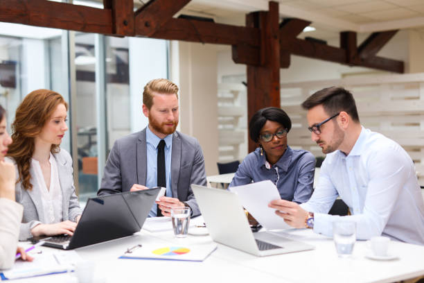 A group of people sitting around a table with papers.