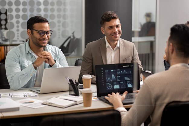 A group of people sitting at a table with laptops.